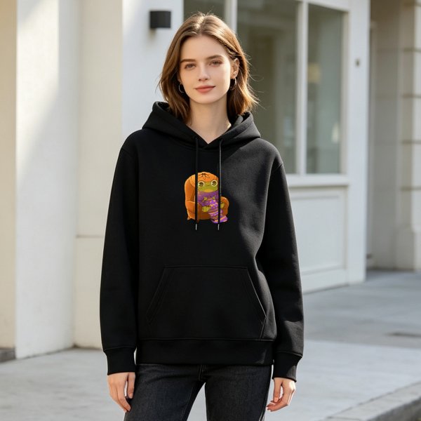 Black hoodie with a cute frog in pumpkin hat sitting on a chair graphic